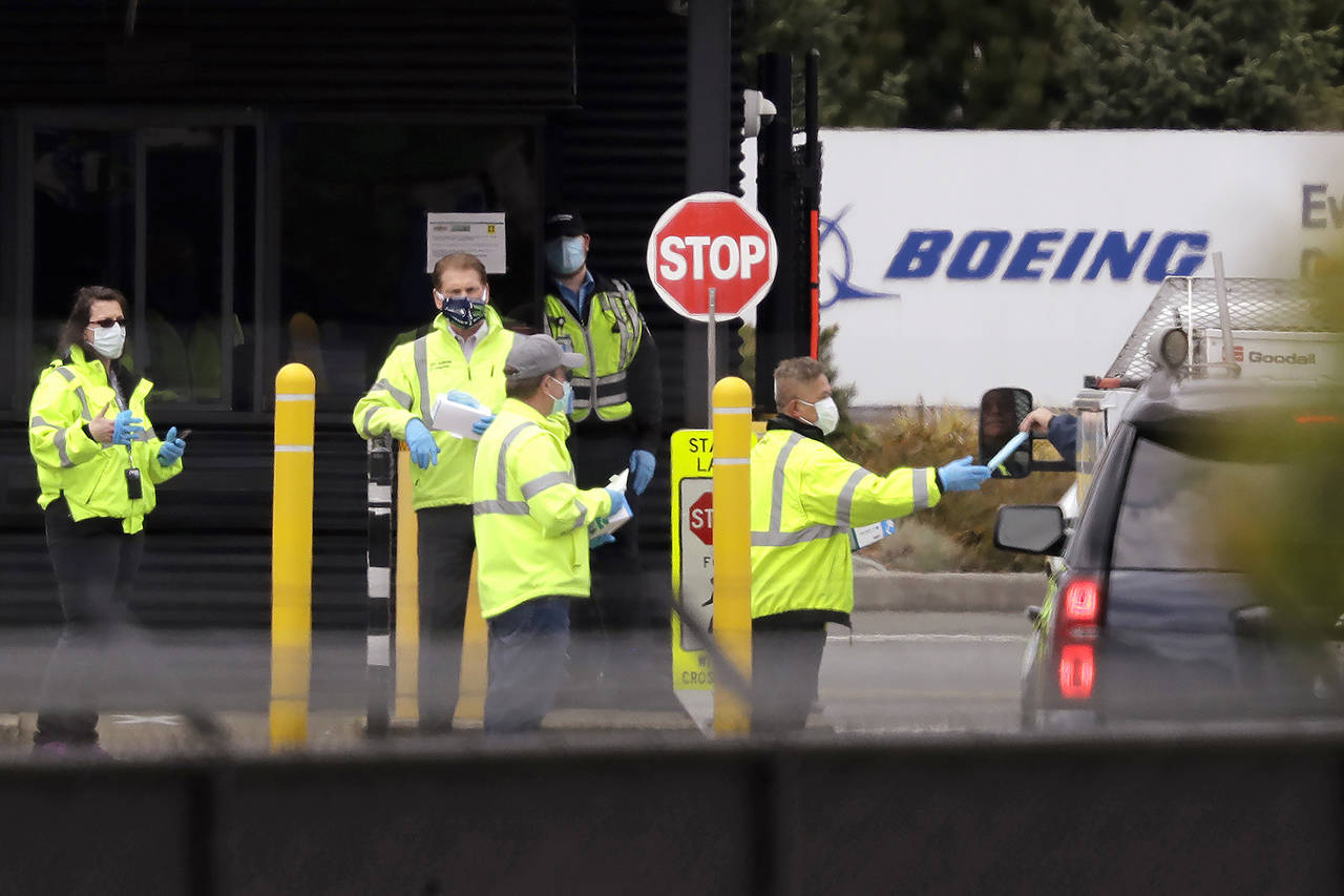 A worker is handed a protective mask while entering a Boeing production plant Tuesday in Everett. (AP Photo/Elaine Thompson)