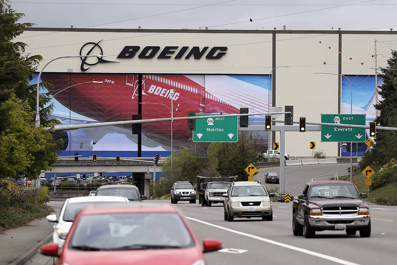 Traffic flows in view of the massive Boeing airplane production plant April 21 in Everett. The company reported a loss of $641 million in the first quarter, while announcing it has started to shrink its workforce through employees volunteering to leave, attrition and “layoffs as necessary.” (AP Photo/Elaine Thompson)