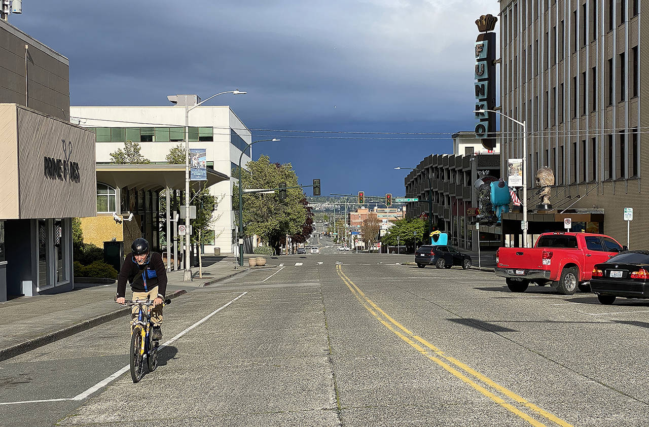 A man rides a bike along the nearly empty downtown streets of Everett on Wednesday afternoon. (Sue Misao / The Herald)
