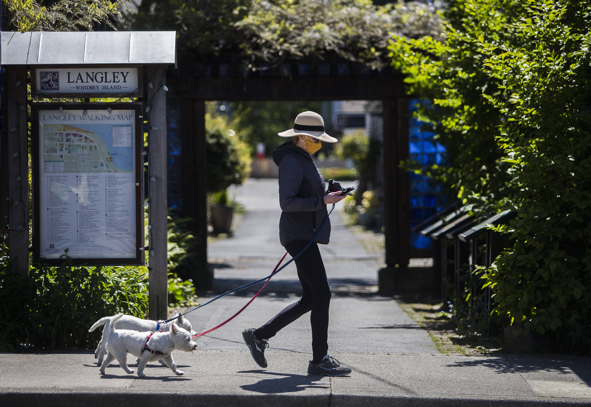 Cally Fulton walks her dogs, Erraid and Oban, on First Street in downtown Langley, where masks are required outside. (Olivia Vanni / The Herald)