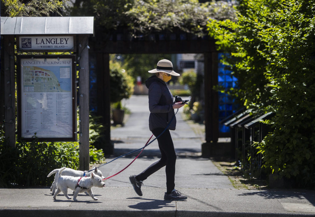 Cally Fulton walks her dogs, Erraid and Oban, on First Street in downtown Langley, where people are required to wear masks inside businesses and outdoors. (Olivia Vanni / The Herald)
