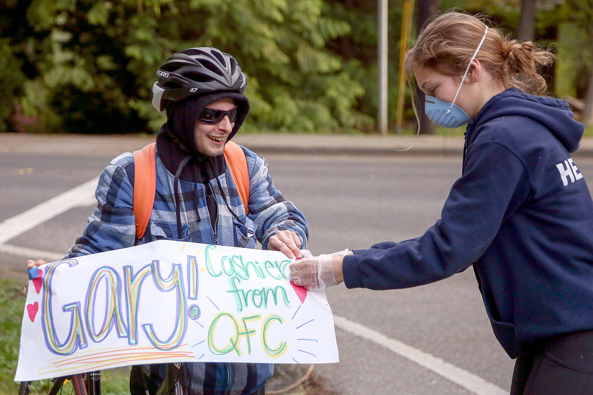 Annabelle Heiman (right) attaches a sign to Gary Locke’s bike in preparation as guest of honor in a parade down 53rd Avenue West in Mukilteo. The block does a “2 minutes of gratitude” nightly tribute to those on the frontlines. (Kevin Clark / The Herald)