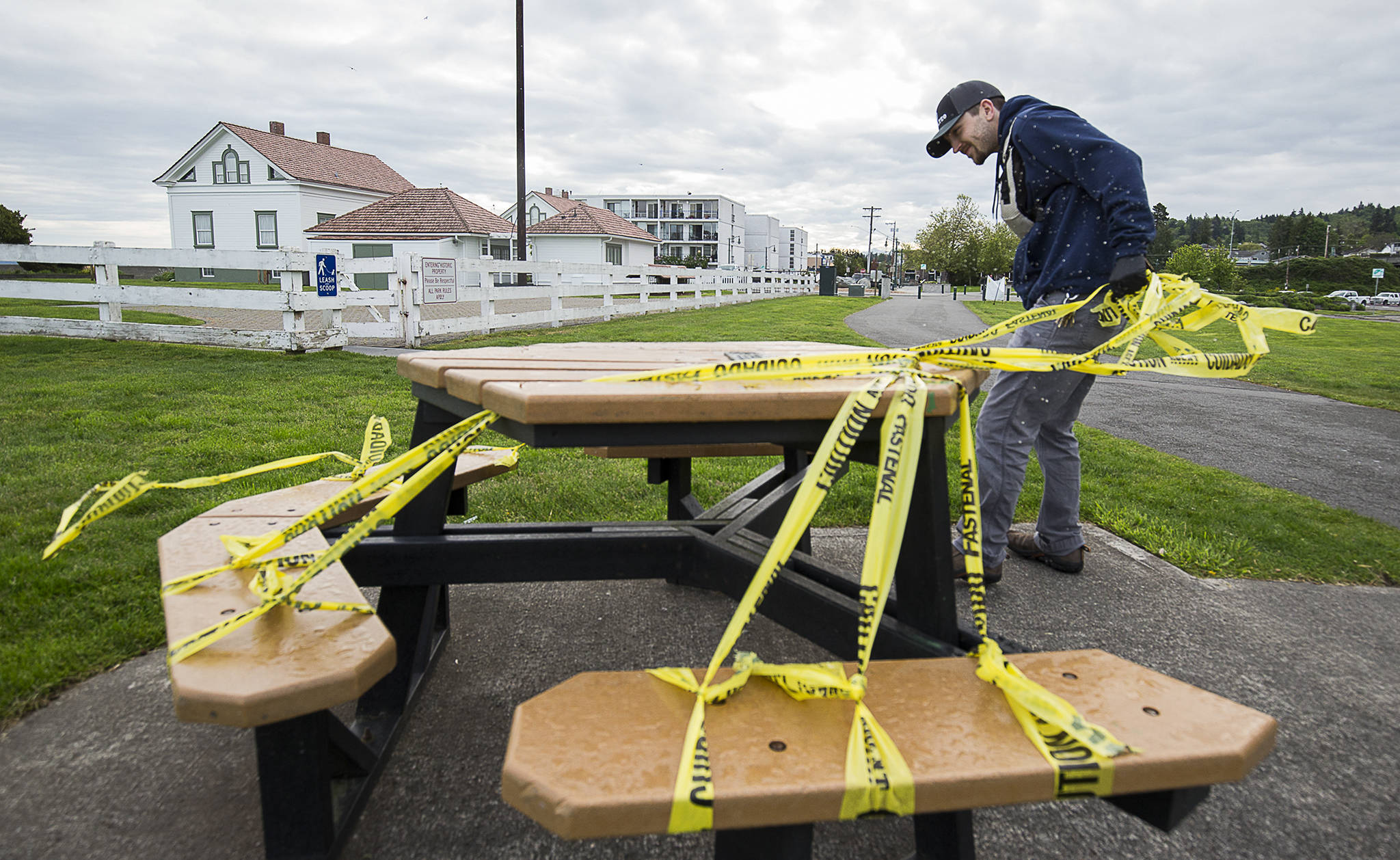 Custodian Bryce Minnich tears off caution tape as Lighthouse Park in Mukilteo reopens Tuesday. (Andy Bronson / The Herald)