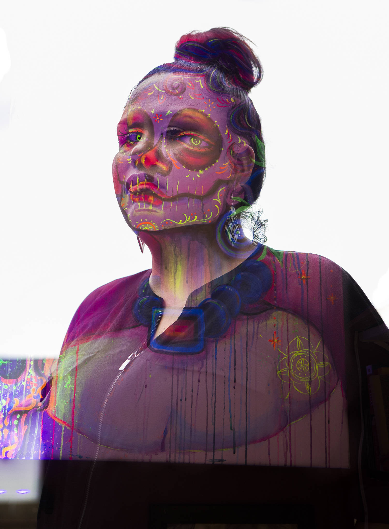 An undocumented woman, who wishes to remain anonymous, photographed with a recent acrylic painting she made Sunday in Everett. This picture is an in-camera double exposure of two images. (Olivia Vanni / The Herald)