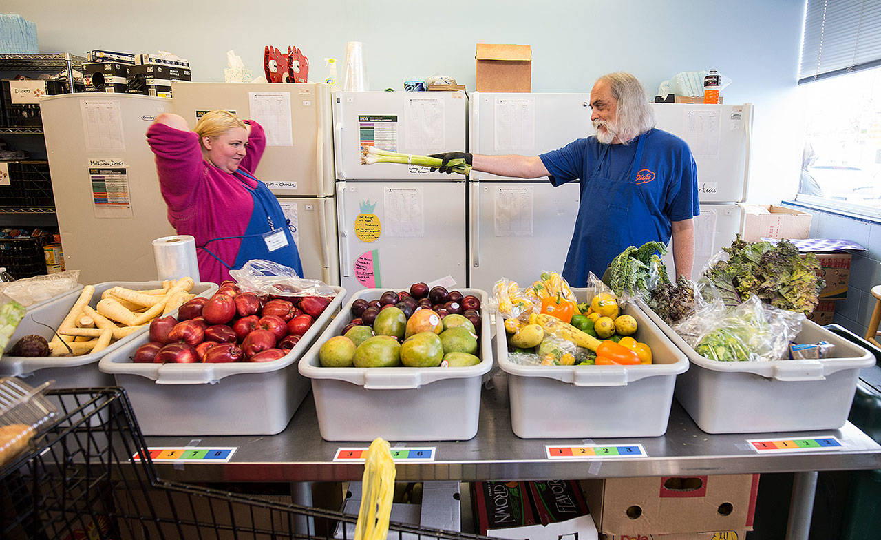 Gary Sterile uses a leek as a wand as he makes a Harry Potter reference to Marika Evenson while volunteering at the Volunteers of America Western Washington’s Everett Food Bank last July in Everett. (Andy Bronson / Herald file photo)