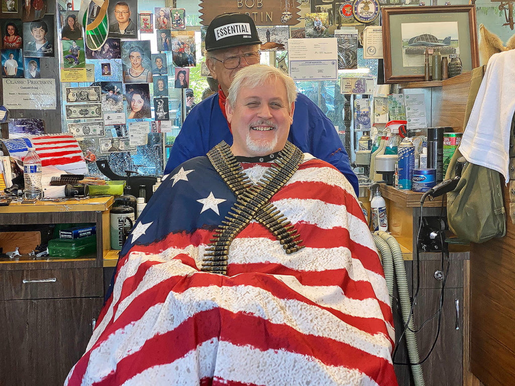 Mike Daniels gets a haircut Tuesday from Bob Martin at Stag Barber and Styling in Snohomish. Dozens of people have lined up since the shop reopened on Saturday. (Andrea Brown / The Herald)
