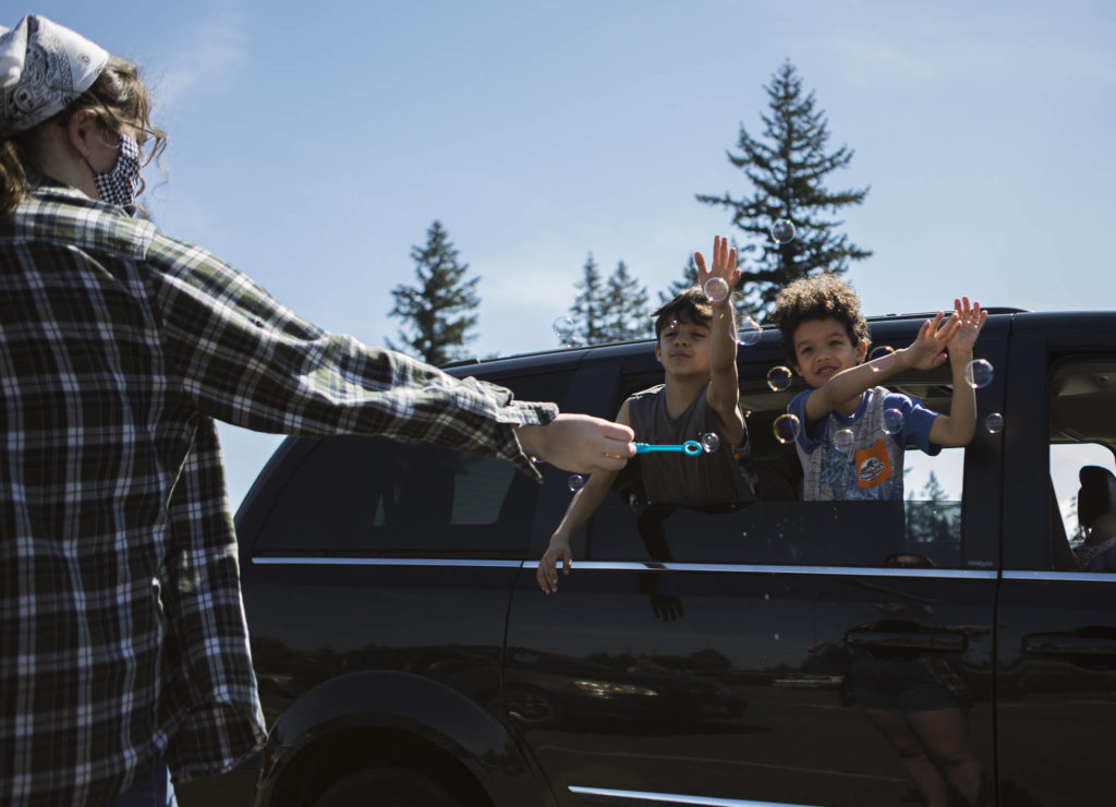 Owyn, 8 (left), and his brother Leon, 6 (right), play with bubbles from the car window while their mom tunes into the church service at the Marysville Foursquare Gospel Church on Sunday. (Olivia Vanni / The Herald)
