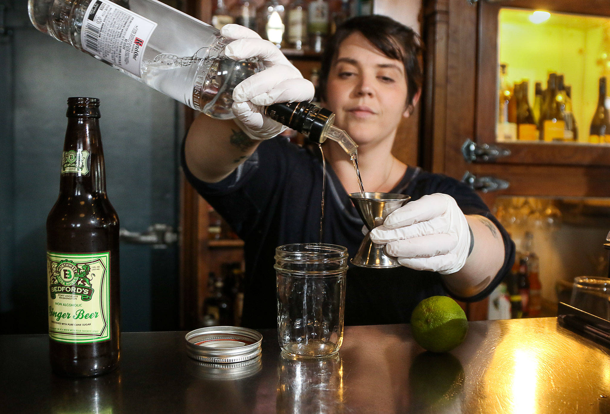 At Buck’s American Cafe in Everett, manager Jasper Mosbacher prepares a cocktail in a glass jar. Bars are now able to serve cocktails for takeout orders. (Andy Bronson / The Herald)