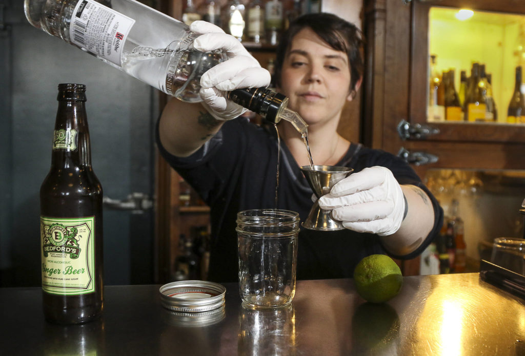 At Buck’s American Cafe in Everett, manager Jasper Mosbacher prepares a cocktail in a glass jar. Bars are now able to serve cocktails for takeout orders. (Andy Bronson / The Herald)
