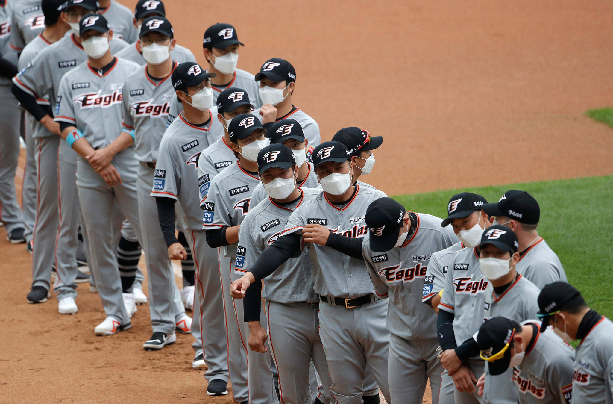 Hanwha Eagles players wearing face masks line up before the start of their game against SK Wyverns on May 5, 2020, in Incheon, South Korea. (AP Photo/Lee Jin-man)