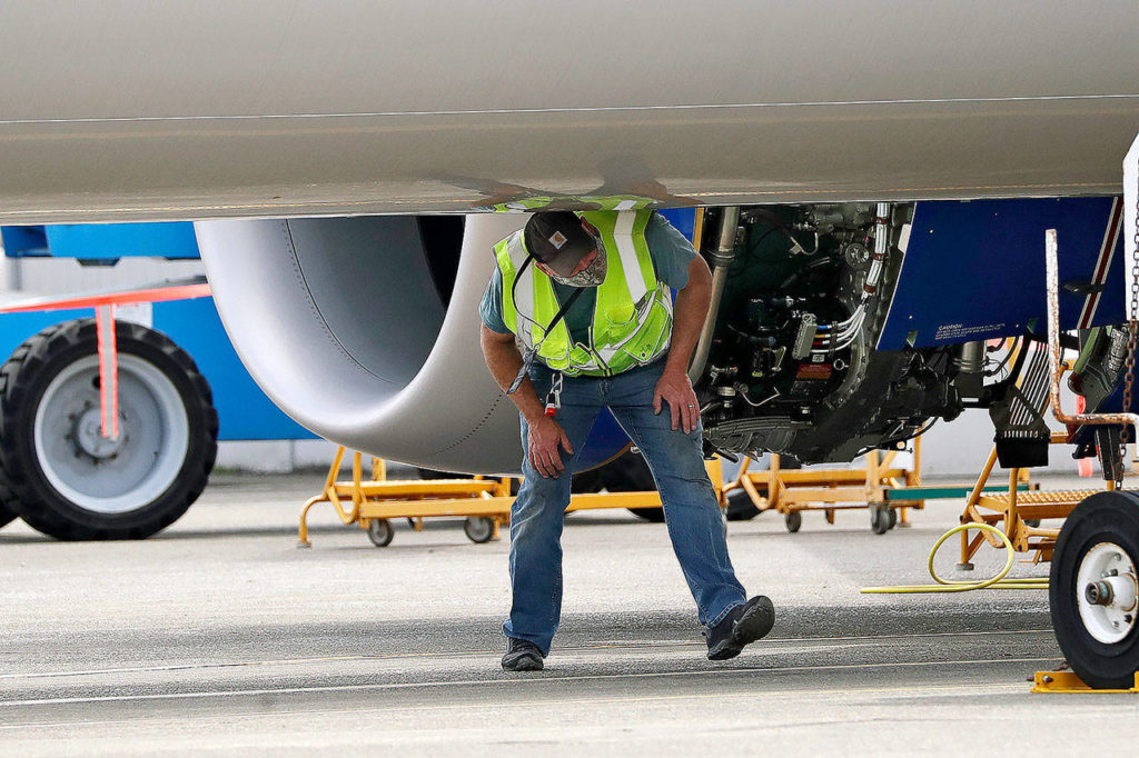 A worker walks under the fuselage of a Boeing 737 Max jet parked at a Boeing airplane manufacturing plant in Renton on April 29. (AP Photo/Elaine Thompson, file)
