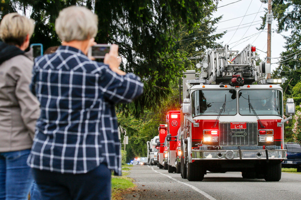 First responders parade past Eli Kincaid’s home Tuesday afternoon in Lynnwood. Before the pandemic, Eli’s family had planned a Make-a-Wish trip to Disneyland. (Kevin Clark / The Herald)
