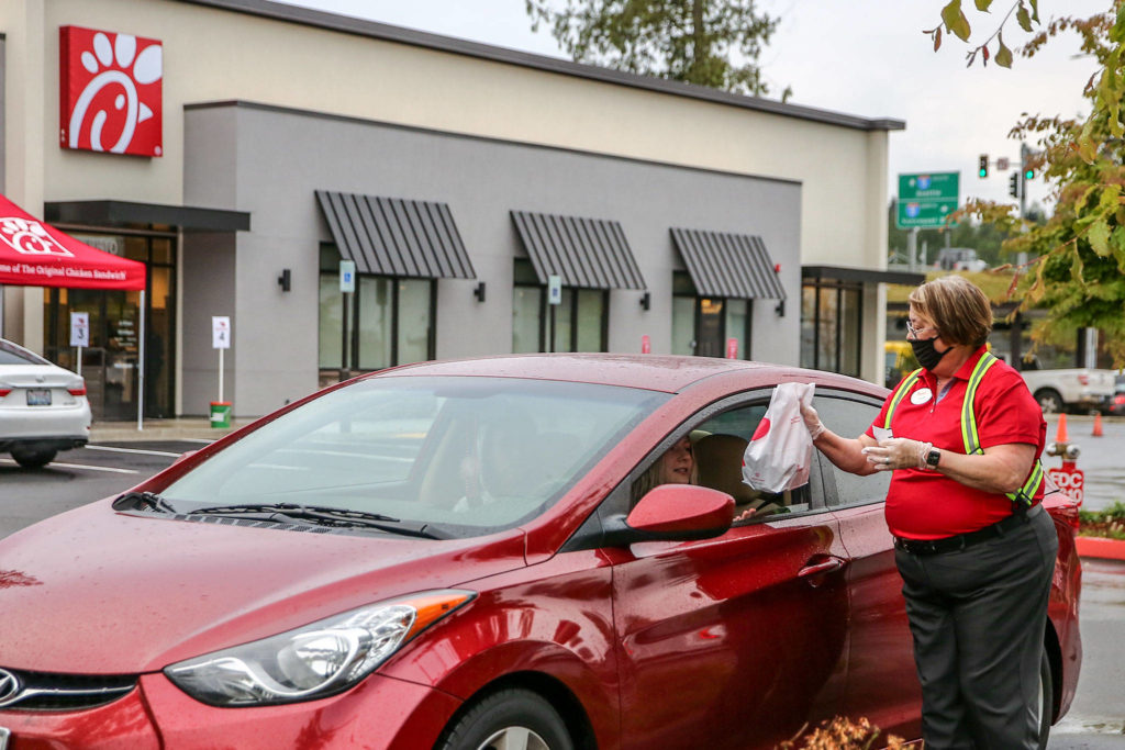 An employee delivers food to one of the first cars in line at Chick-fil-A’s new restaurant in Marysville on Thursday. (Kevin Clark / The Herald)
