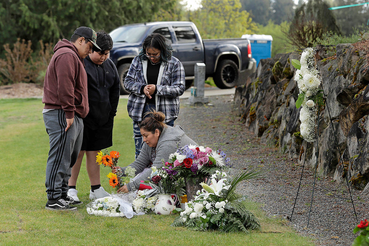 In this April 23 photo, Antonia Lopez (lower right) places flowers at the grave of her husband, Tomas Lopez, 44, who died of COVID-19 on April 2. Their children Isaac, 19 (left), Elias, 12 (second from left) and Elda, 16 (upper right) look on at the Mountain View Cemetery in Auburn. (AP Photo/Ted S. Warren, File)