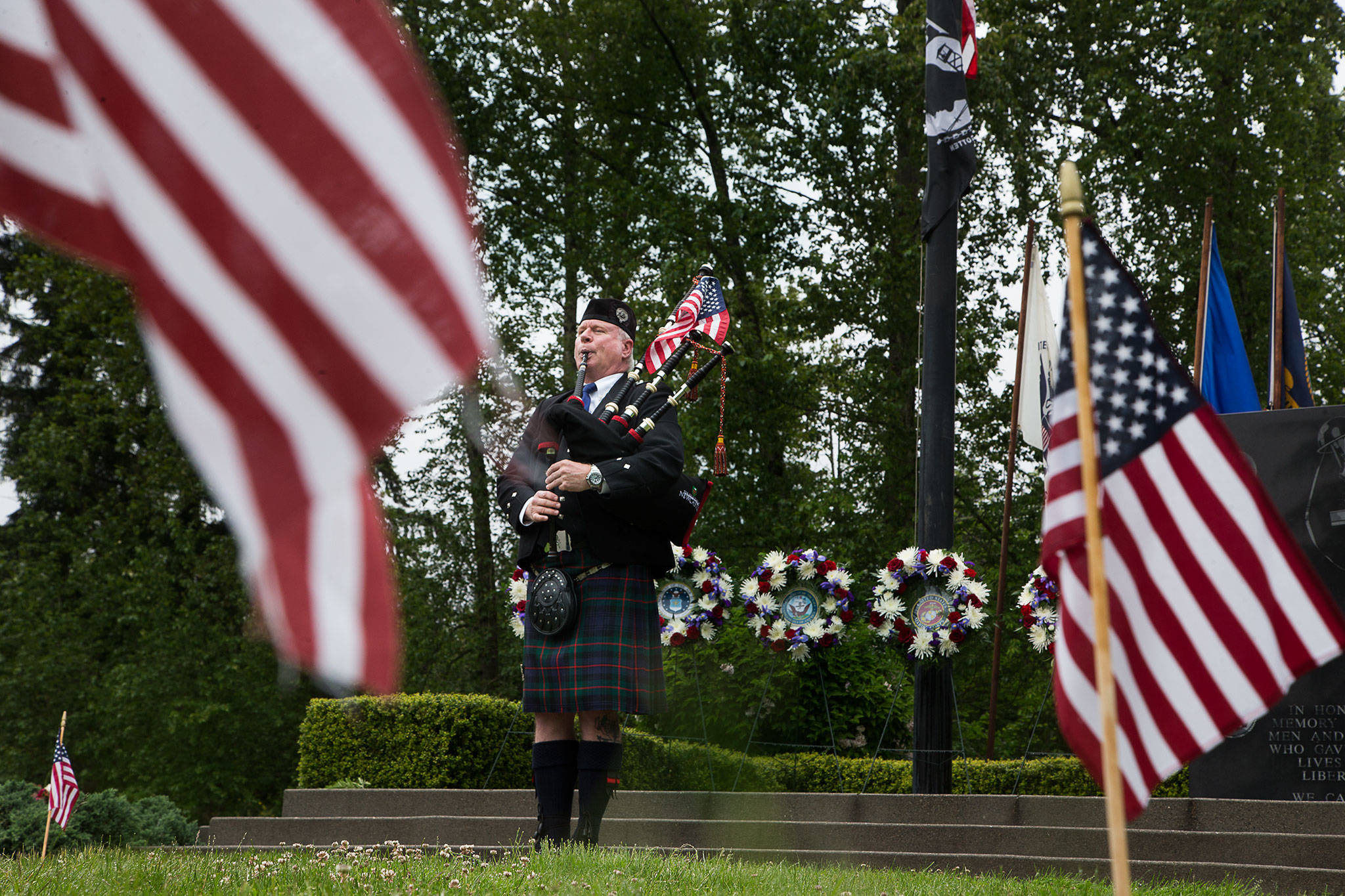 Neil Hubbard plays the bagpipes in front of a memorial at Floral Hills cemetery in Lynnwood Monday morning. (Andy Bronson / The Herald)