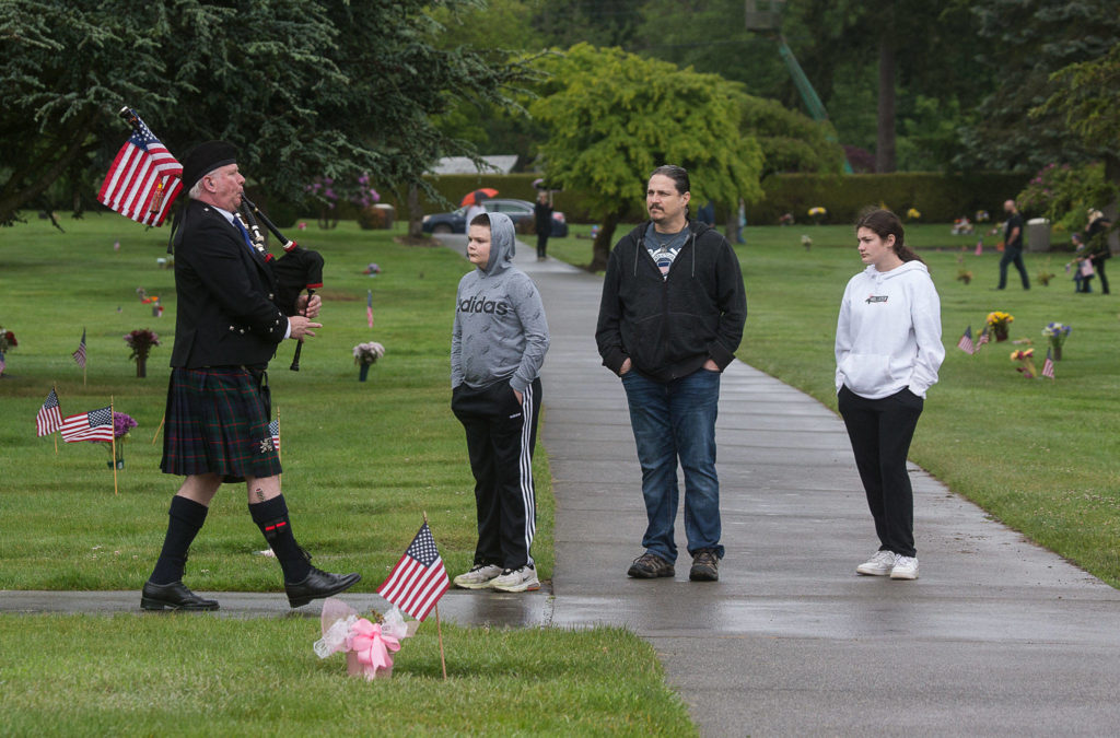 Bagpiper Neil Hubbard plays while marching past visitors Monday at Floral Hills cemetery in Lynnwood. (Andy Bronson / The Herald)

