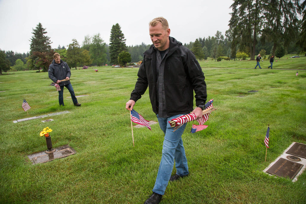 Former U.S. Marines Garth Lindelef, right, and Sean Hunt display flags on veteran grave markers at Floral Hills cemetery on Monday. The duo stopped to pay respects to a fellow fallen Marine. (Andy Bronson / The Herald)
