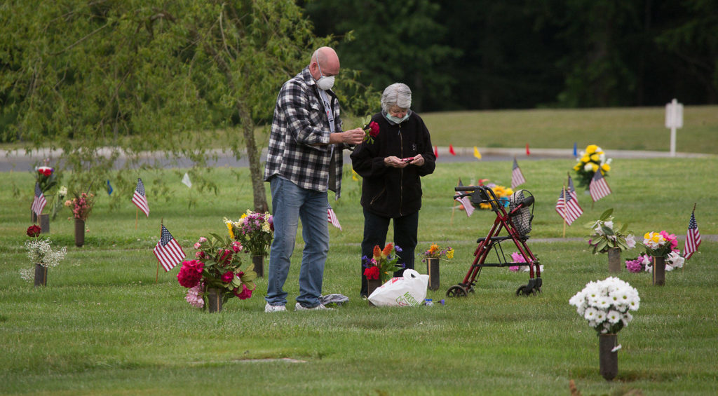Ben Johnson helps his mother, Sadie, arrange flowers for his father, Ben, Monday at Floral Hills cemetery in Lynnwood. (Andy Bronson / The Herald)
