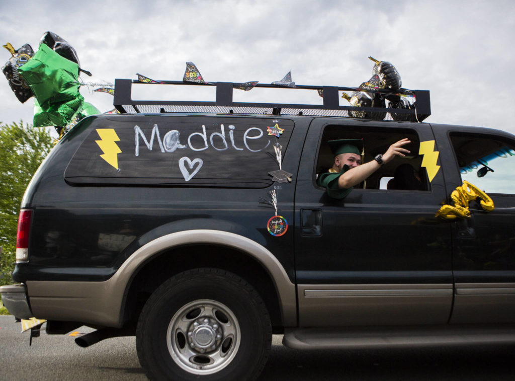 A Marysville Getchell High School graduate waves out of their car as people cheer during the Marysville-Tulalip All High School Senior Parade on Friday, May 29, 2020 in Marysville, Wa. (Olivia Vanni / The Herald)

