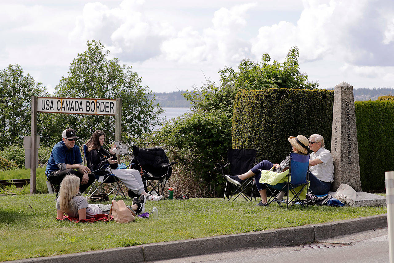 In this May 17 photo, Sylvie Tortorelli (on grass) visits with her parents for the first time in 10 weeks at the border between the U.S. and Canada in Peace Arch Park, in Blaine. (AP Photo/Elaine Thompson)