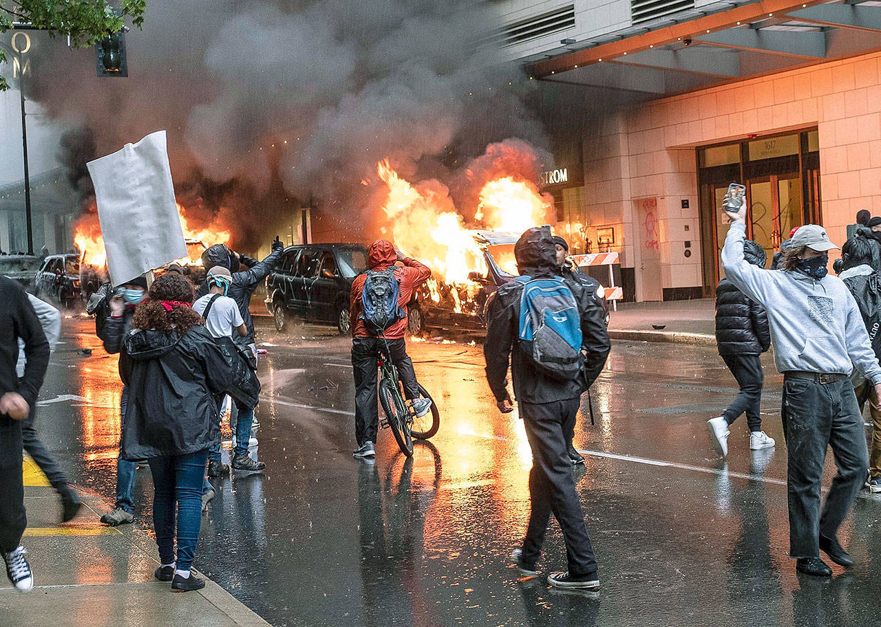People set fire to vehicles during a protest Saturday in Seattle. Protests were held throughout the country over the death of George Floyd, a black man who died after being restrained by Minneapolis police officers May 25. (Dean Rutz/The Seattle Times via AP)