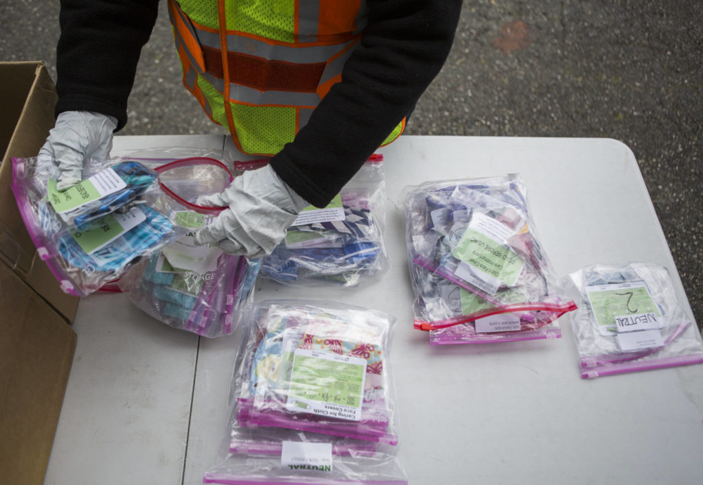 Martha Mee sorts through masks that are organized by age and size in Everett. (Olivia Vanni / The Herald) 
