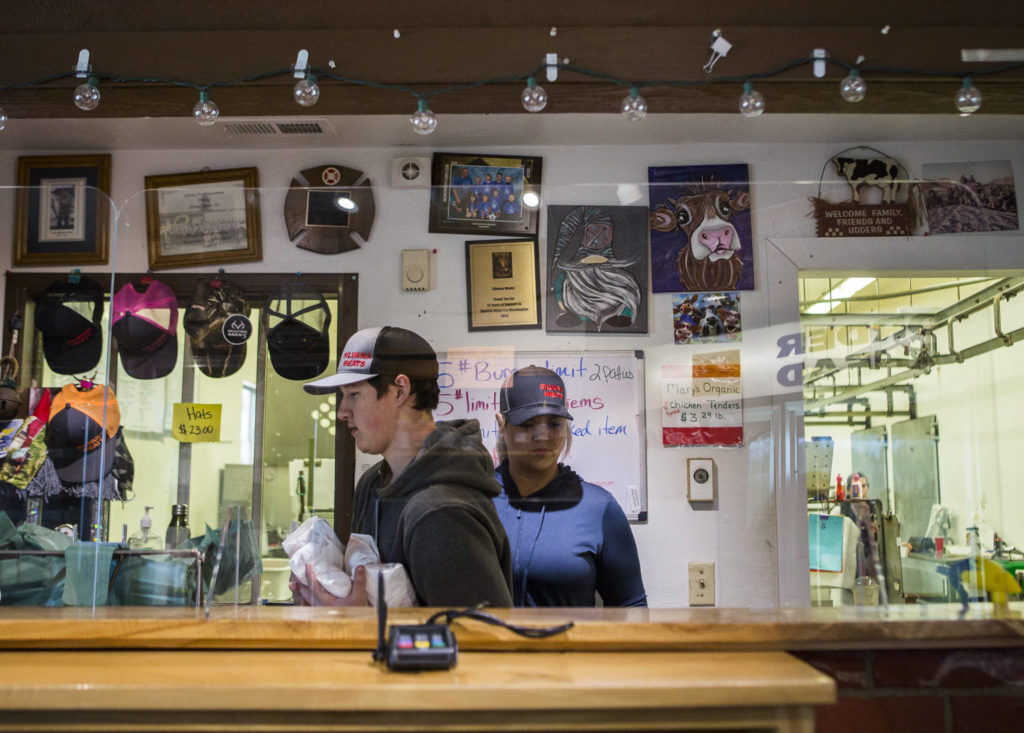 Kevin Faulkner, left, and Sarah Floe take customer orders from behind plexiglass at Silvana Meats on Friday, May 29, 2020 in Silvana, Wa. (Olivia Vanni / The Herald)
