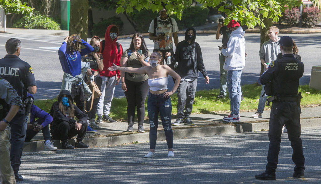 Lynnwood police listen as a young woman complains after being confronted when she and others wandered past barricades at the Alderwood mall on Monday in Lynnwood. (Andy Bronson / The Herald)

