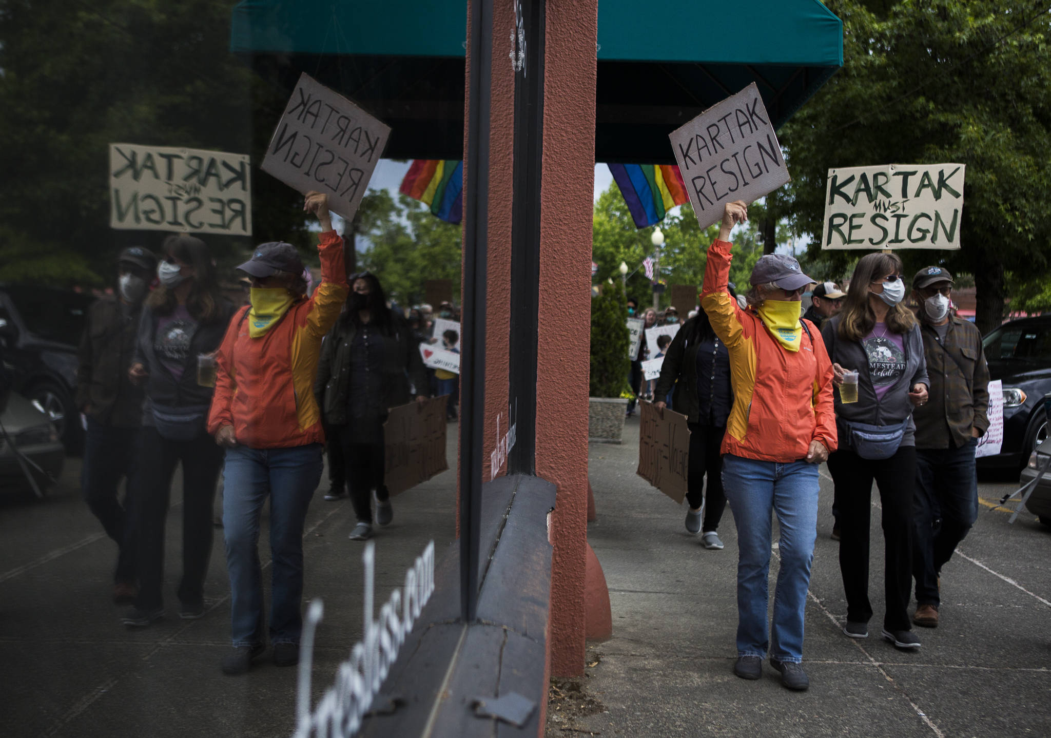 A group of protesters holding signs calling for Snohomish Mayor John Kartak’s resignation walk down First Street on Friday in Snohomish. (Olivia Vanni / The Herald)