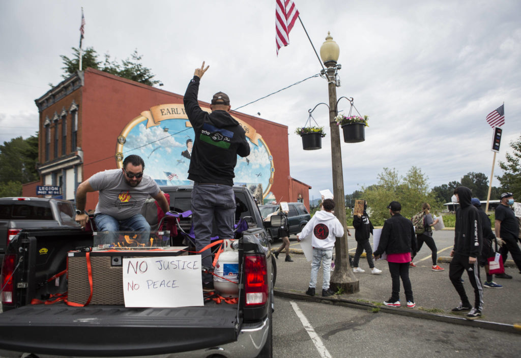 Scott Elmer (left) and Nathan Vrentas (right) protest along First Street from the back of their truck on Friday in Snohomish. (Olivia Vanni / The Herald)
