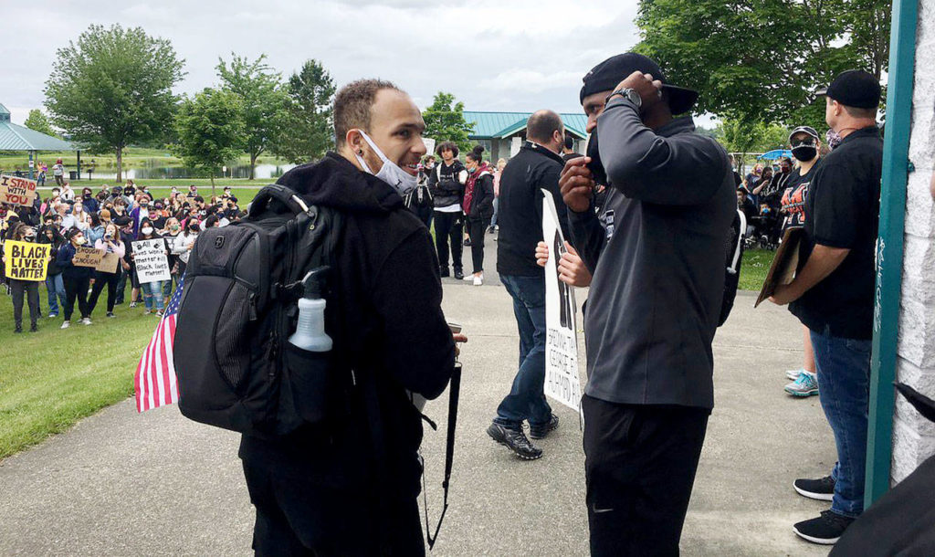 Organizer Isaiah Cole (left) greets his former high school football coach Michael Bumpus (right) at the Justice March for George Floyd in Monroe on Wednesday. (Nick Patterson / The Herald)
