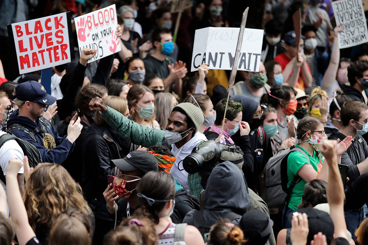 Activist David Lewis (center) walks through a crowd of protesters as he heads into Seattle City Hall to meet with the mayor Wednesday in Seattle, following protests over the death of George Floyd, a black man who was in police custody in Minneapolis. (AP Photo/Elaine Thompson)
