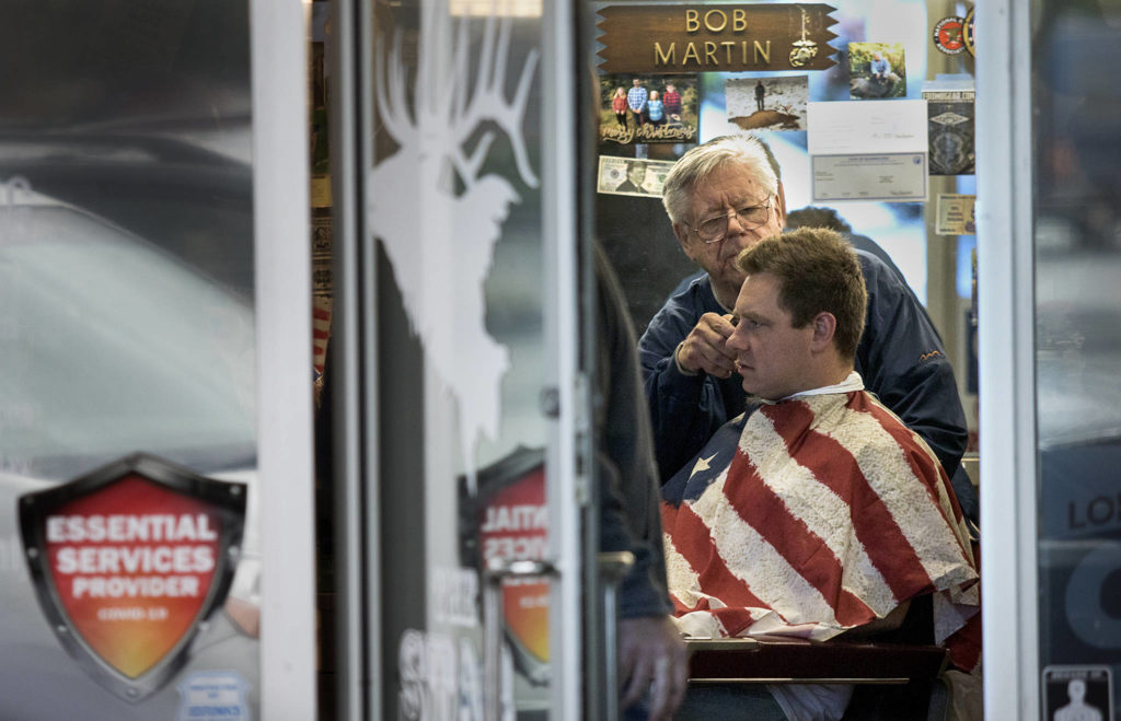 In defiance of Gov. Jay Inslee’s stay-home order, owner Bob Martin cuts a customer’s hair at The Stag barbershop in Snohomish last month. (Andy Bronson / The Herald)
