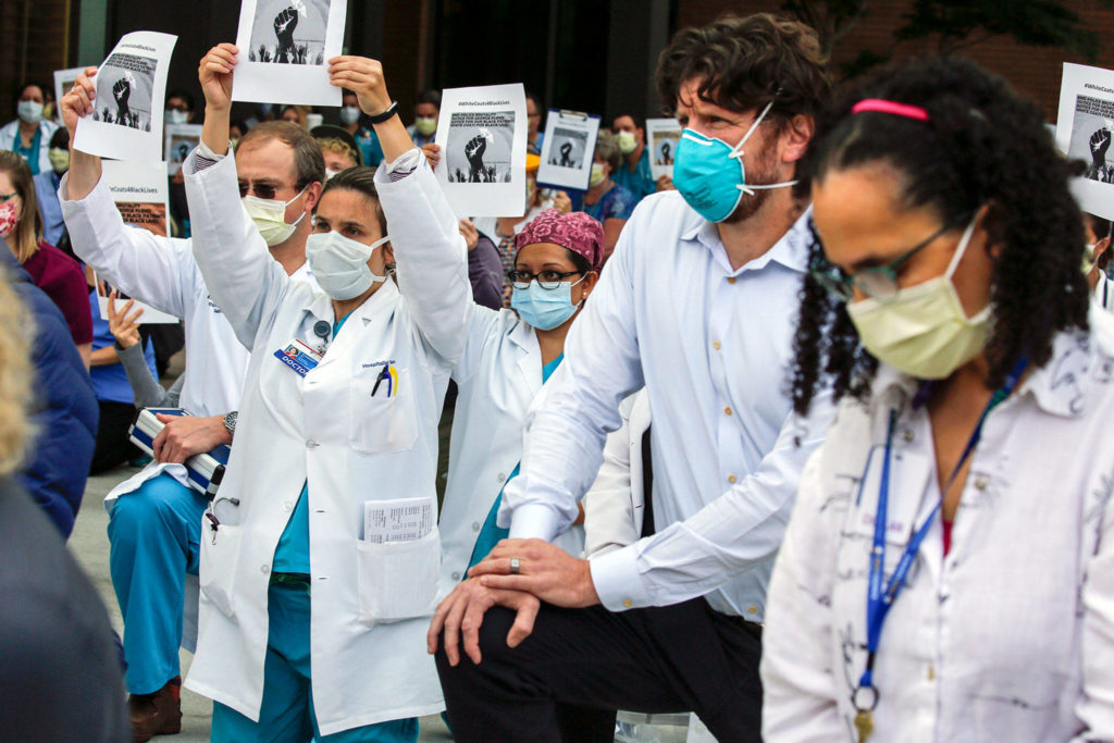 Health care workers take a knee for 10 minutes as part of White Coats 4 Black Lives at Providence Regional Medical Center Everett on Friday morning. (Kevin Clark / The Herald)
