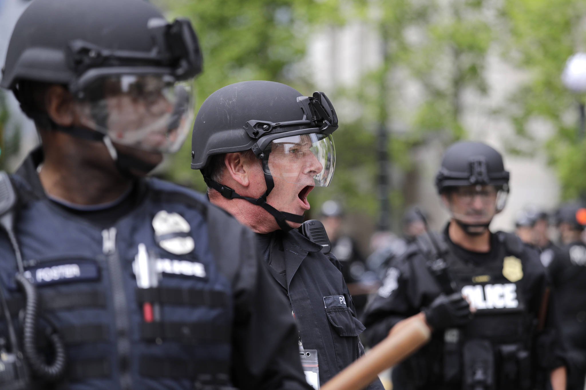 A Seattle police officer yells out orders at Seattle City Hall as protesters march toward them Wednesday, June 3, 2020, in Seattle, following protests over the death of George Floyd, a black man who died in police custody in Minneapolis. (AP Photo/Elaine Thompson)