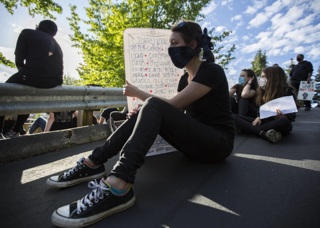 Kylara Triel uses her sign to shield herself from the sun during the Black Lives Matter protest on Sunday in Mukilteo. (Olivia Vanni / The Herald)
