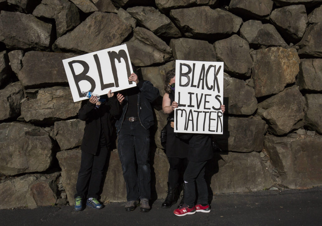 Protesters use their signs to shield themselves from the sun during the Black Lives Matter protest on Sunday in Mukilteo. (Olivia Vanni / The Herald)
