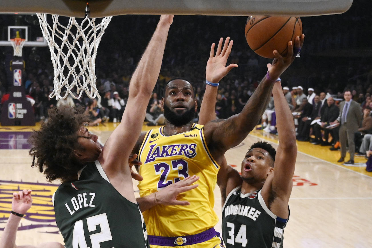 Los Angeles Lakers forward LeBron James, center, shoots as Milwaukee Bucks center Robin Lopez, left, and forward Giannis Antetokounmpo defend during the first half of an NBA basketball game on March 6 in Los Angeles. (AP Photo/Mark J. Terrill)