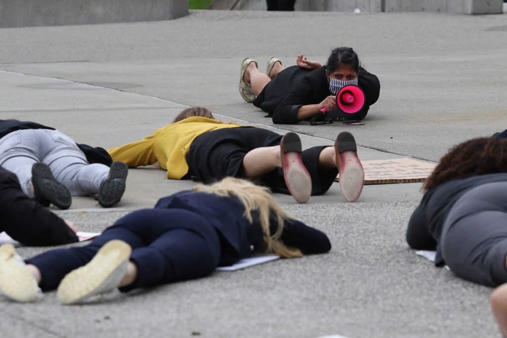 Snohomish County public defender Nikita Parekh chants through a megaphone as the crowd lies on the ground for 8 minutes and 46 seconds, as long as a Minneapolis police officer held a knee on George Floyd’s neck before he died. (Andy Bronson / The Herald)

