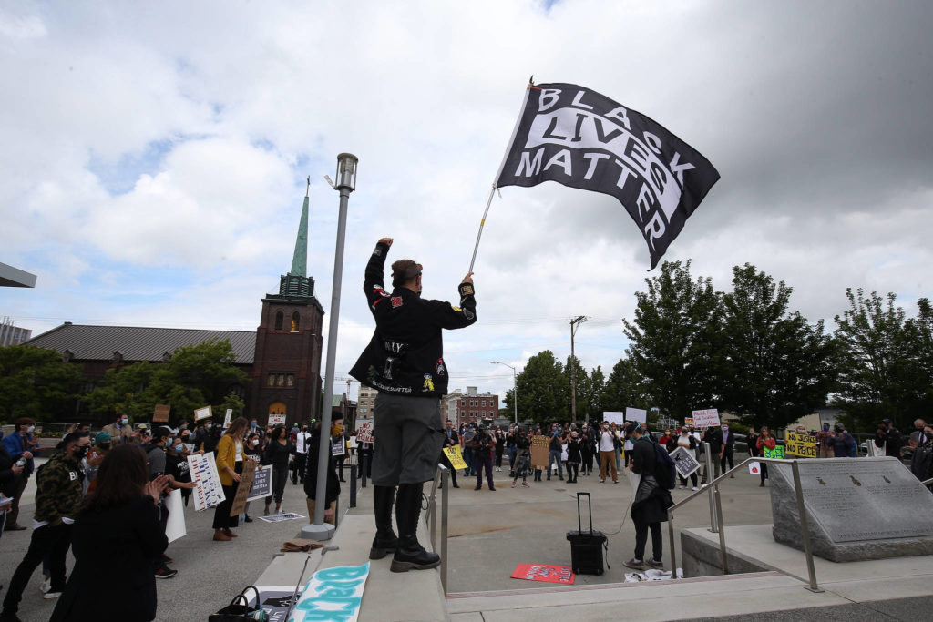 A protester waves a Black Lives Matter flag outside the Snohomish County Courthouse on Monday. (Andy Bronson / The Herald)
