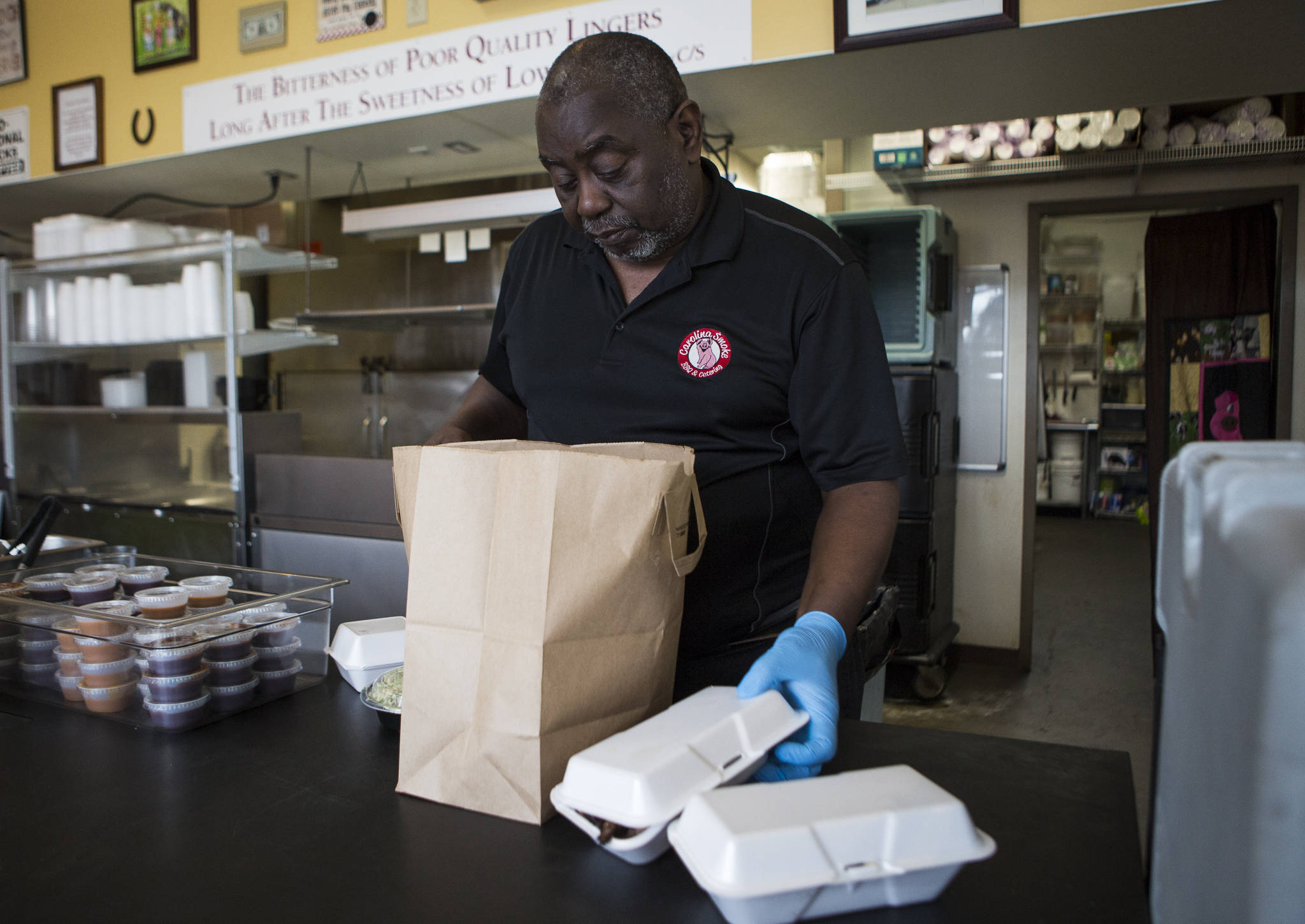 Carolina Smoke owner David Hayward packages up orders to go at his Bothell restaurant. (Olivia Vanni / The Herald)