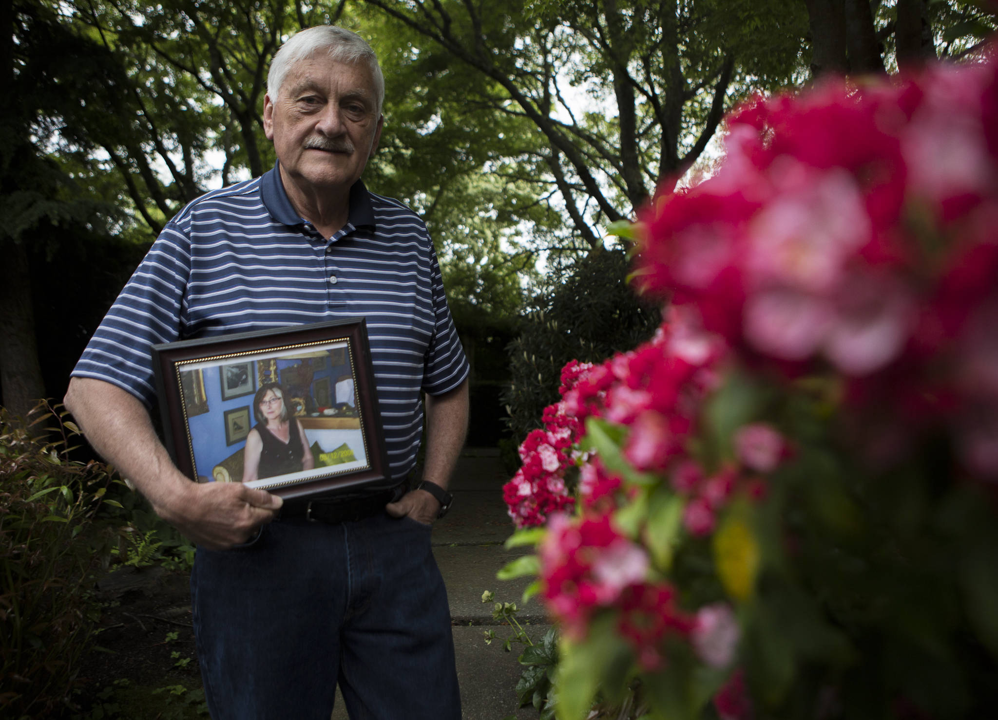 Larry Jubie holds a photograph of his sister Christine Jubie outside his home on Friday in Everett. Christine Jubie, who lived at a care facility in Everett, died of COVID-19 on June 2. She was 67. (Olivia Vanni / The Herald)