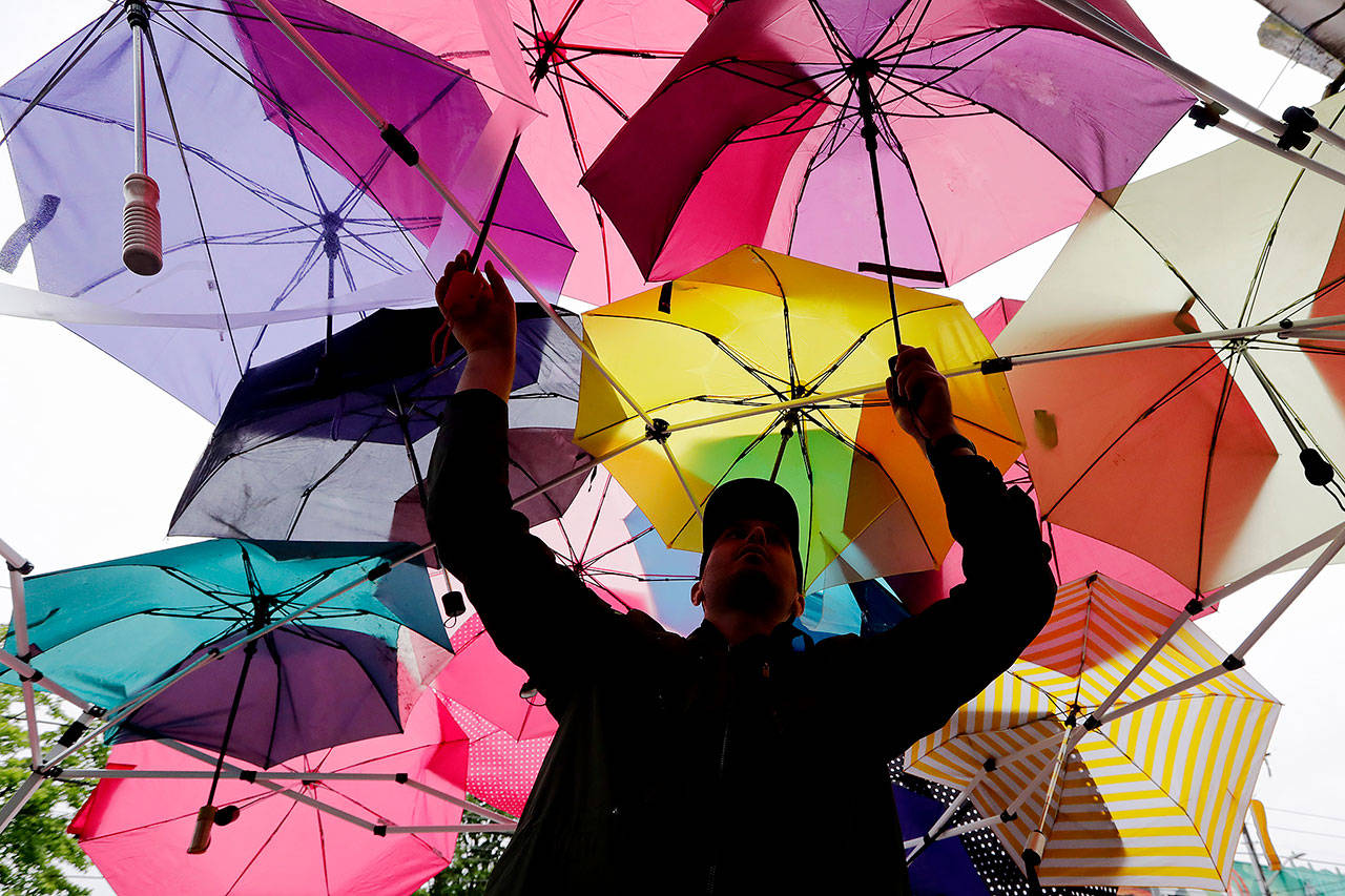 Protester Andrew Tomes adjusts umbrellas being used after a tarp was forgotten at a site supplying food and other essentials to demonstrators near a closed Seattle police precinct Tuesday in Seattle, following protests over the death of George Floyd, a black man who was in police custody in Minneapolis. (AP Photo/Elaine Thompson)