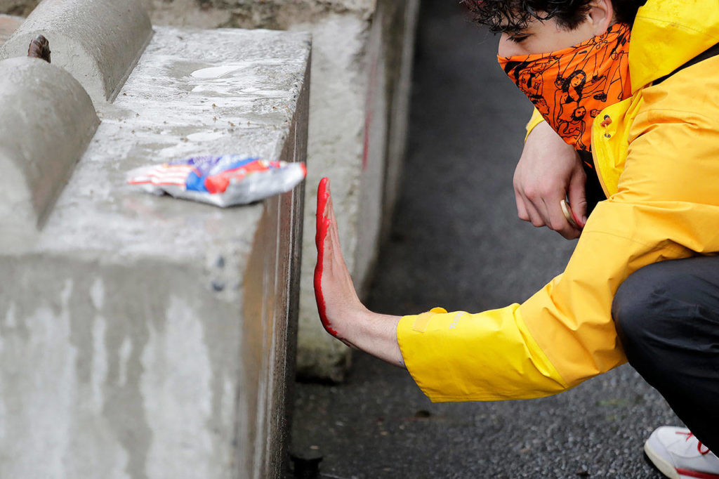 A man leaves a red paint handprint on a barricade near a closed Seattle police precinct Tuesday in Seattle, following protests over the death of George Floyd. (AP Photo/Elaine Thompson)
