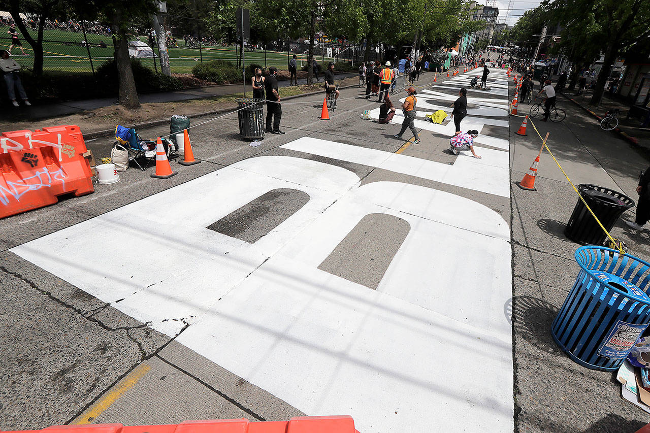 People work to dry off large letters that read “Black Lives Matter” painted on a street near Cal Anderson Park on Thursday, inside what is being called the “Capitol Hill Autonomous Zone” in Seattle. (AP Photo/Ted S. Warren)