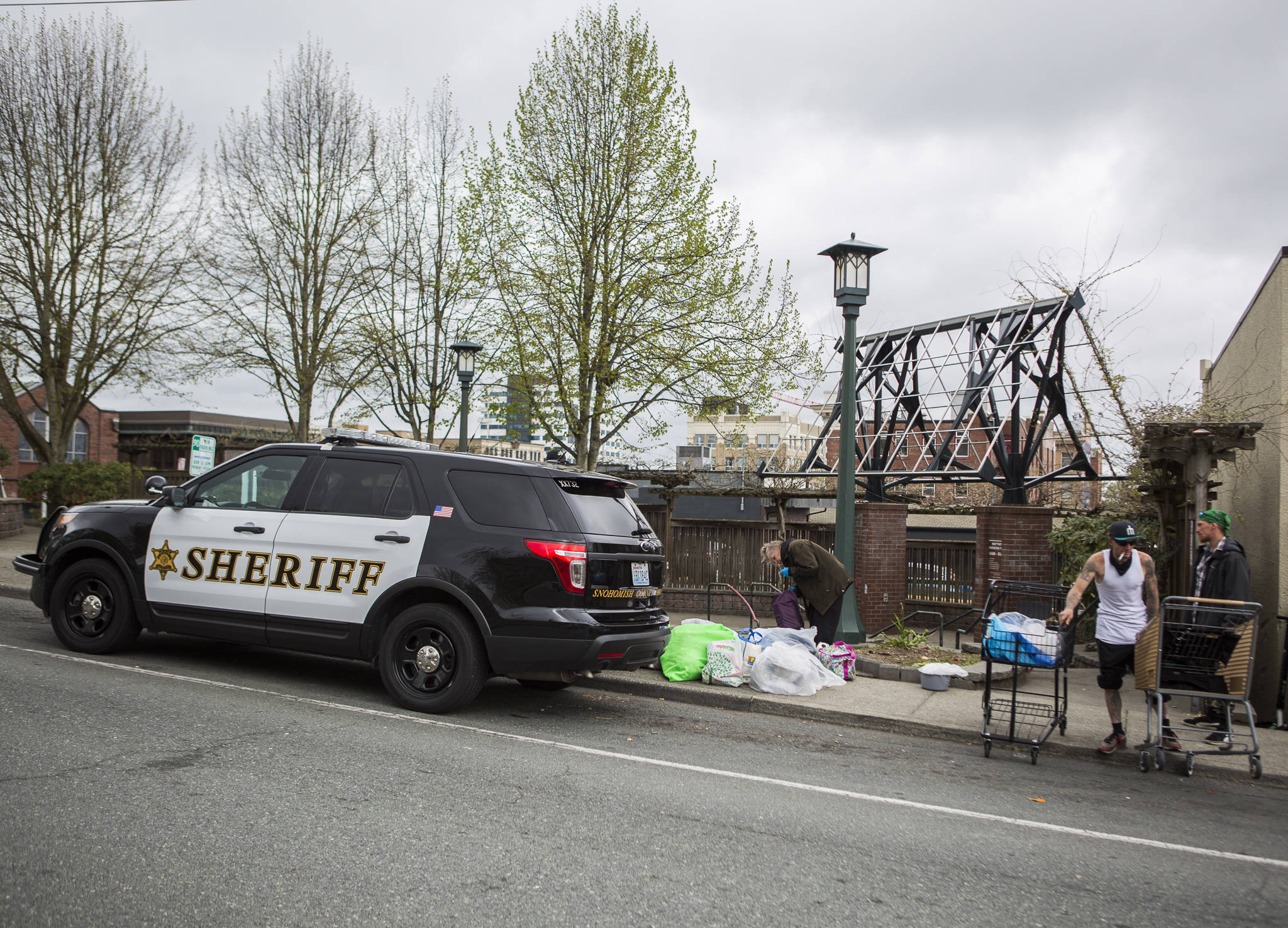 Snohomish County Sheriff’s deputies clear out the remaining people from a homeless camp at Matthew Parsons Memorial Park this April in Everett. Budgets and the ‘Defund Police’ movement prompted a six-hour public hearing discussion before the Snohomish County Council last week. (Olivia Vanni / Herald file photo)