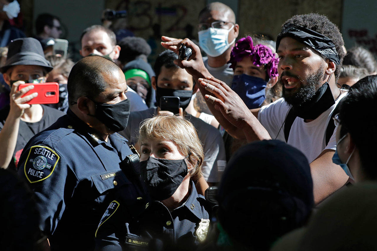A protester who did not give his name talks with Seattle Police assistant chiefs Adrian Diaz (left) and Deanna Nollette Thursday inside what is being called the “Capitol Hill Autonomous Zone” in Seattle.(AP Photo/Ted S. Warren)