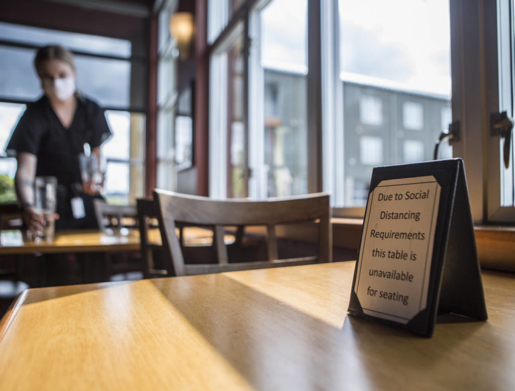 An empty table has a sign alerting customers to social distancing guidelines at Lombardi’s Italian Restaurant on Saturday in Everett. (Olivia Vanni / The Herald)
