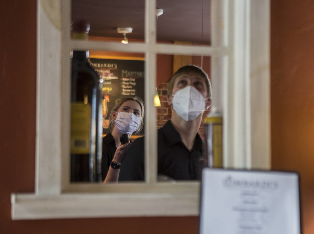 Kayla Salatino and Paulmer Gregory change the television channel in the bar at Lombardi’s Italian Restaurant on Saturday in Everett. Bar seating no longer is allowed at the restaurant. (Olivia Vanni / The Herald)
