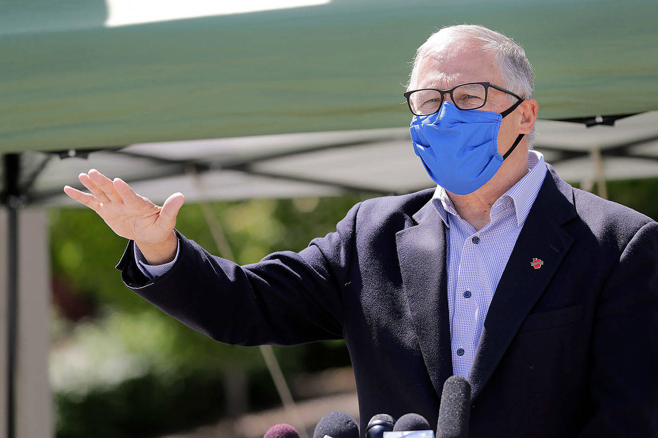 Washington Gov. Jay Inslee motions about the high rate of coronavirus cases in the area during a news conference at Yakima Valley College on Tuesday. (AP Photo/Elaine Thompson)